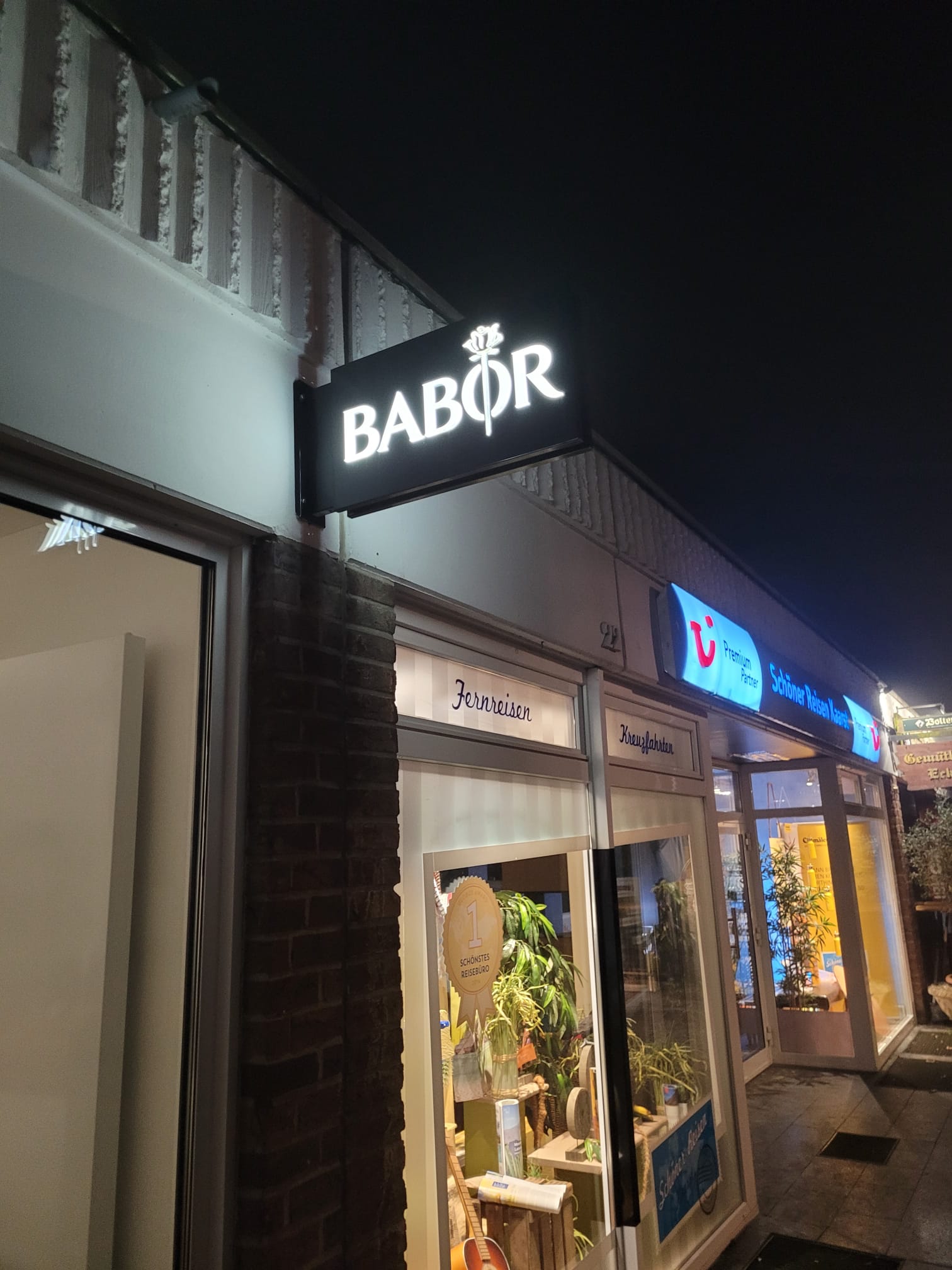 Beleuchtetes BABOR-Schild über dem Eingang bei Nacht