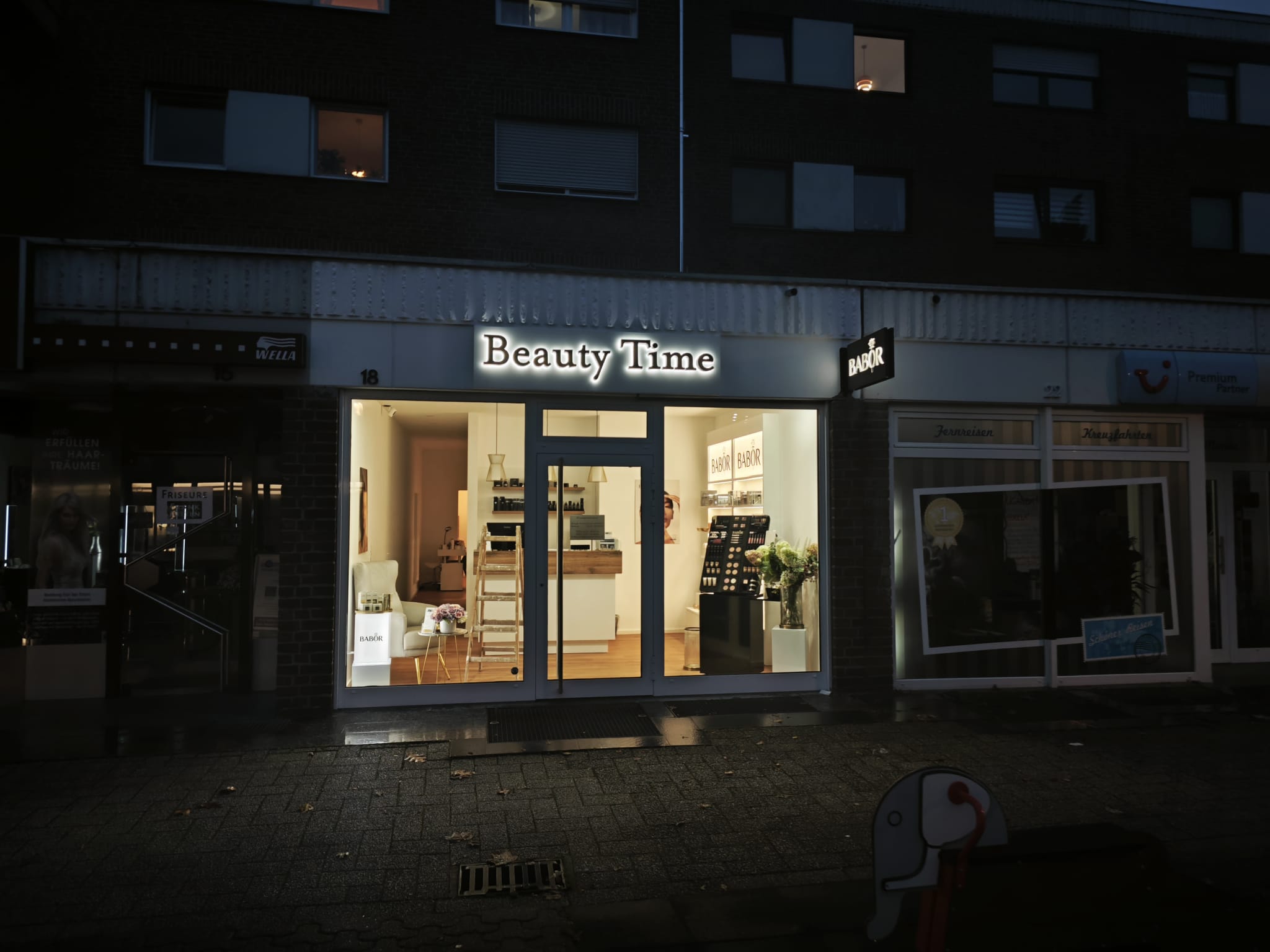Beleuchtete Ladenfront von Beauty Time am Abend