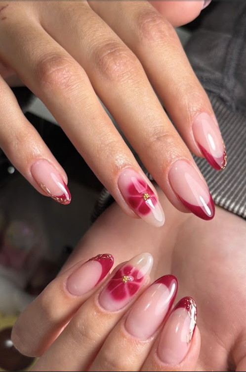 Nageldesign mit roter French-Spitze und Blüte, beide Hände in Nahaufnahme